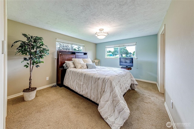 bedroom with baseboards, a textured ceiling, and light colored carpet