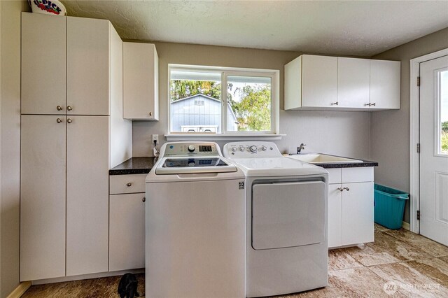 laundry area featuring a sink, a healthy amount of sunlight, cabinet space, and washer and dryer