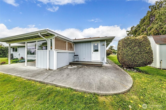 rear view of house featuring a lawn, an outbuilding, a patio area, and a storage unit