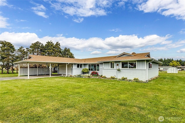 single story home with aphalt driveway, a storage shed, board and batten siding, a front yard, and a carport