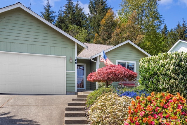 ranch-style home with a garage, a shingled roof, and driveway