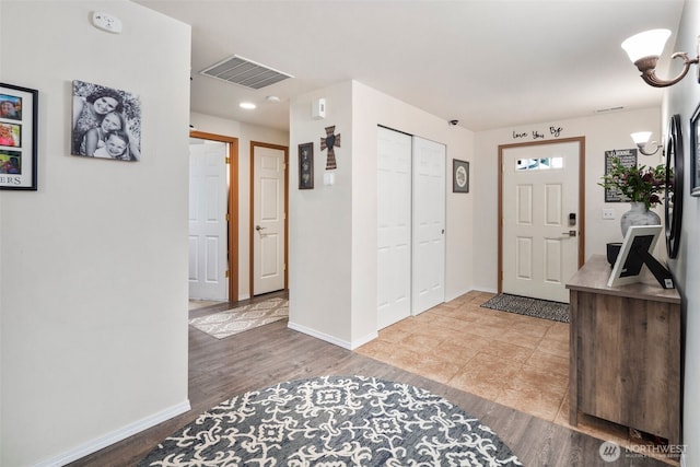 foyer entrance featuring baseboards, wood finished floors, and visible vents