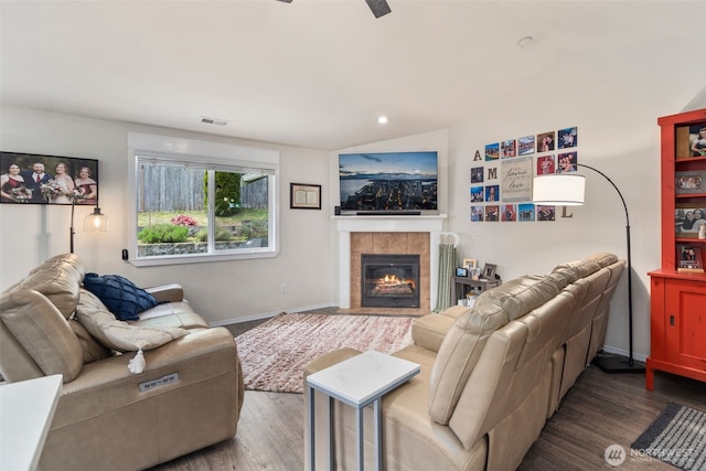 living room featuring visible vents, baseboards, wood finished floors, and a tiled fireplace