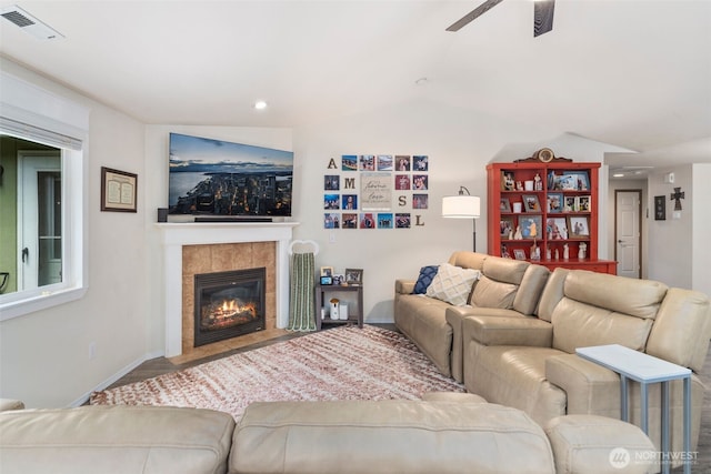 living room featuring baseboards, a fireplace, a ceiling fan, and visible vents
