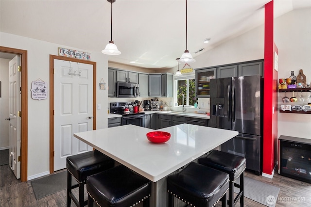 kitchen featuring visible vents, electric range oven, black fridge with ice dispenser, gray cabinetry, and stainless steel microwave