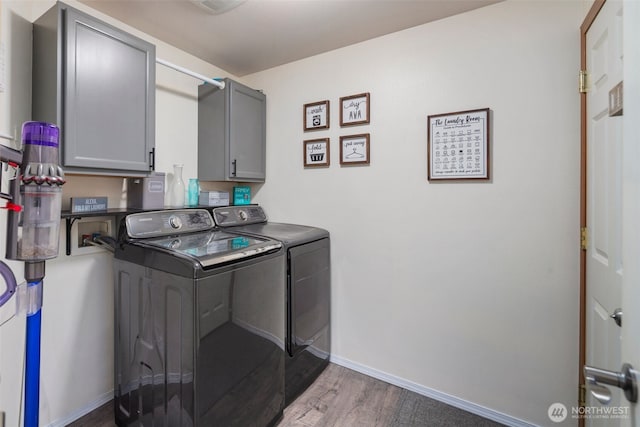 laundry room with wood finished floors, baseboards, cabinet space, and washer and clothes dryer