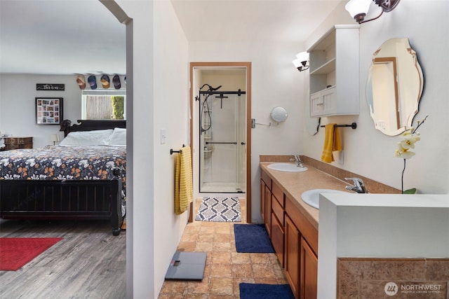 ensuite bathroom with a sink, ensuite bathroom, a shower stall, and wood finished floors