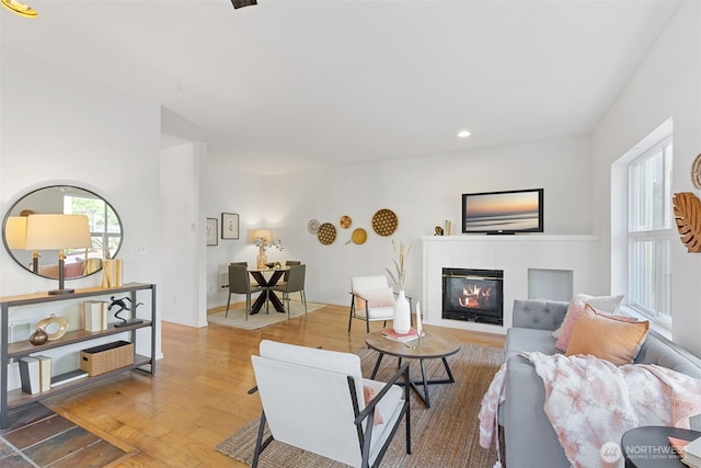 living area with wood finished floors, a tile fireplace, and recessed lighting