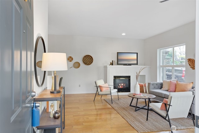 living area featuring light wood-style floors, a tiled fireplace, recessed lighting, and baseboards