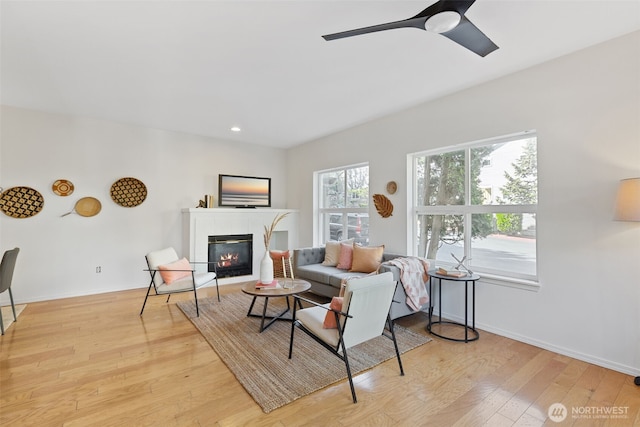 living room featuring a tiled fireplace, light wood-style flooring, baseboards, recessed lighting, and ceiling fan