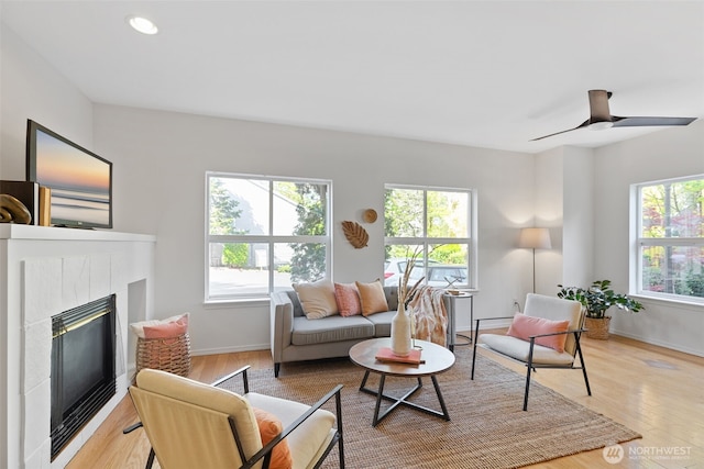 living room featuring light wood-style flooring, baseboards, a glass covered fireplace, and recessed lighting