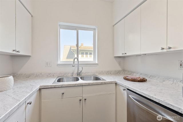 kitchen with stainless steel dishwasher, a sink, white cabinetry, and light countertops