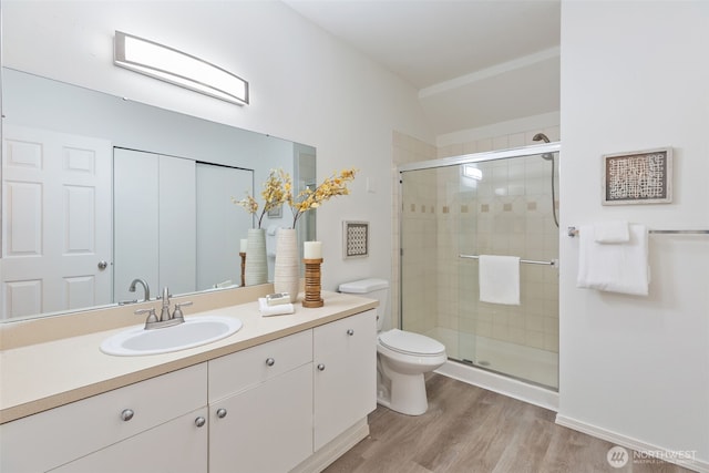 full bath with a shower stall, wood finished floors, toilet, and vanity