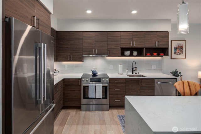 kitchen with a sink, light countertops, stainless steel appliances, and light wood-type flooring