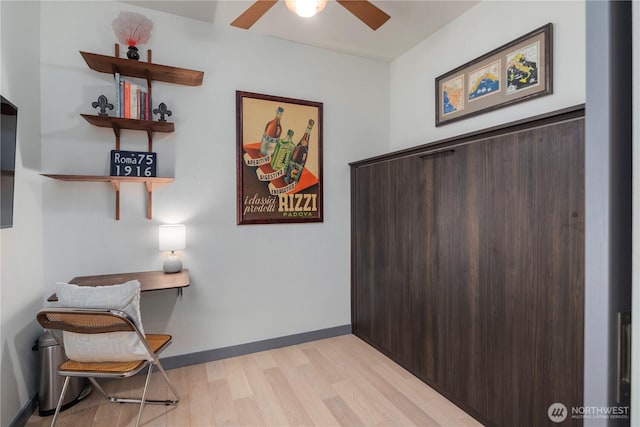 sitting room featuring baseboards, a ceiling fan, and light wood-style flooring