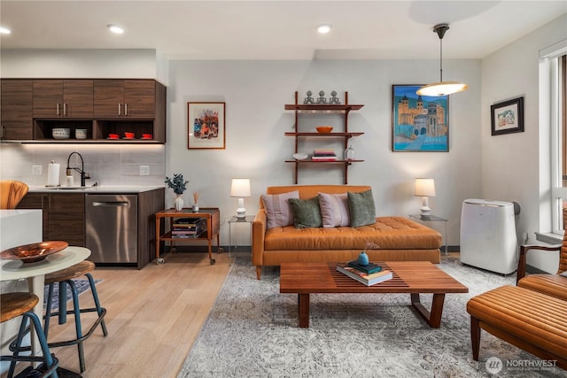 living room with light wood-style floors, recessed lighting, and wet bar