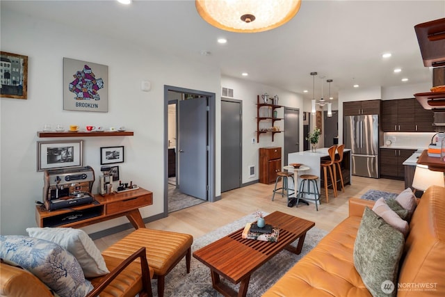 living room with recessed lighting, visible vents, and light wood finished floors