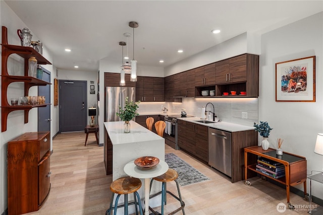 kitchen featuring open shelves, a sink, a center island, stainless steel appliances, and light wood-type flooring