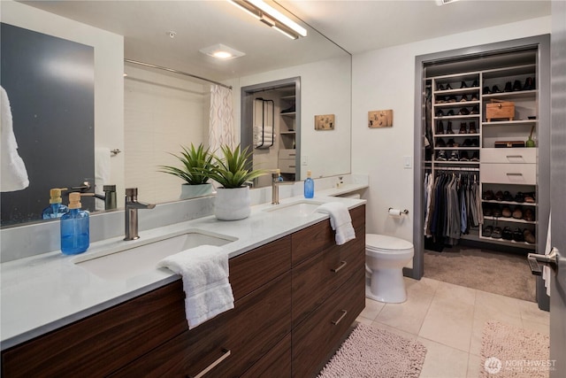 full bath featuring double vanity, a sink, a walk in closet, and tile patterned flooring