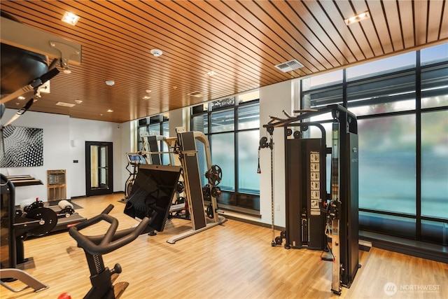 gym with a wall of windows, wooden ceiling, wood finished floors, and visible vents