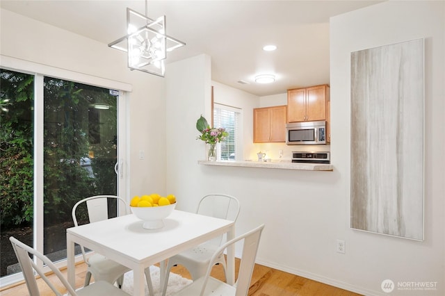 dining area with baseboards, light wood finished floors, and a chandelier