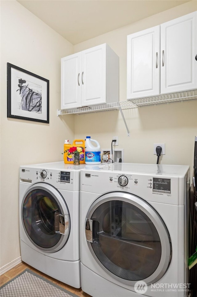 washroom featuring separate washer and dryer, cabinet space, and baseboards
