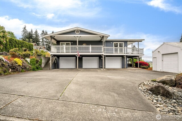 view of front of home with stairs, an attached garage, covered porch, and concrete driveway