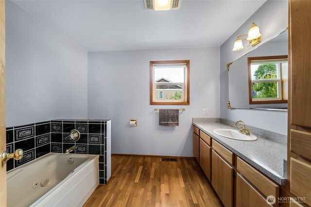 bathroom featuring visible vents, a whirlpool tub, wood finished floors, and vanity