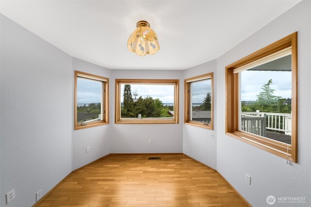 empty room with light wood-style flooring and visible vents