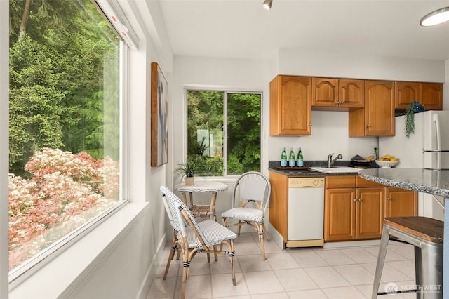 1156 Alki Ave SW Unit 401, Seattle, WA 98116 - kitchen featuring white dishwasher, a sink, brown cabinetry, and light tile patterned floors