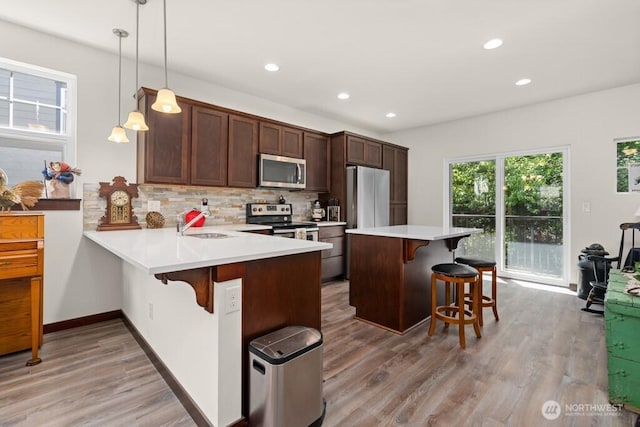 kitchen with backsplash, stainless steel appliances, recessed lighting, and a kitchen breakfast bar