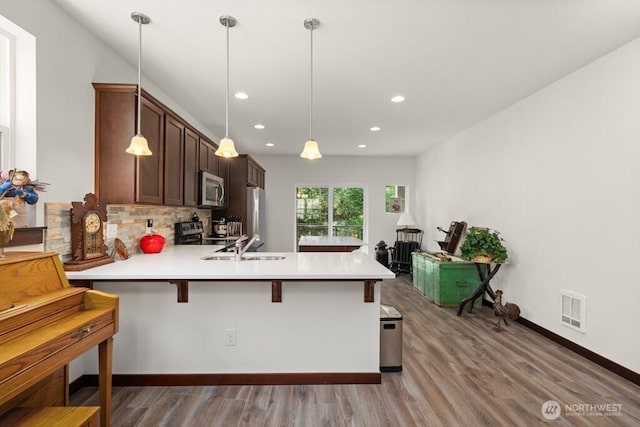 kitchen with recessed lighting, light countertops, a peninsula, and stainless steel appliances