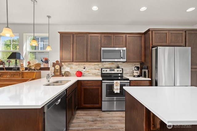 kitchen with light wood-type flooring, a sink, light countertops, and stainless steel appliances