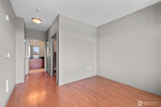 spare room featuring wood finished floors, a smoke detector, and baseboards