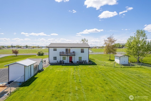 rear view of house with a lawn, an outdoor structure, a fenced backyard, and a balcony