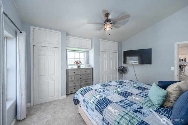 bedroom featuring light carpet, multiple closets, a ceiling fan, baseboards, and lofted ceiling