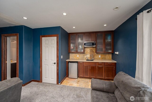 interior space featuring decorative backsplash, a sink, baseboards, stainless steel microwave, and light carpet
