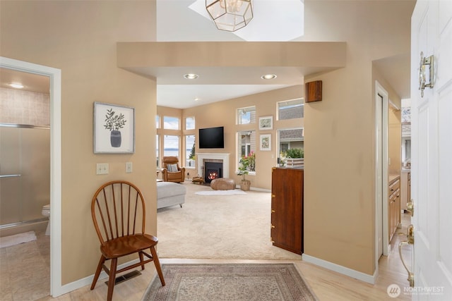 corridor with a high ceiling, baseboards, a skylight, recessed lighting, and light colored carpet