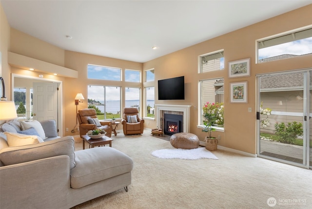 living area with carpet flooring, a fireplace, recessed lighting, and a towering ceiling