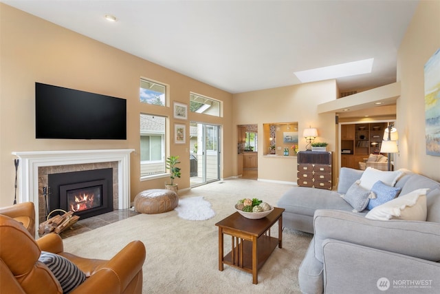 carpeted living area with a fireplace, a skylight, and a towering ceiling
