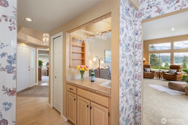 bar area with a chandelier, wallpapered walls, recessed lighting, light wood-style flooring, and a sink
