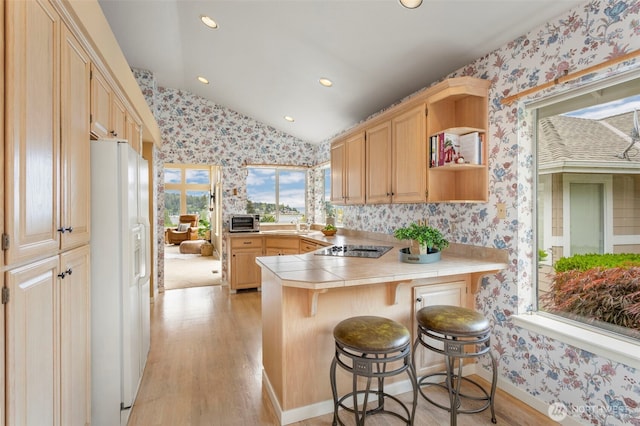 kitchen with wallpapered walls, white fridge with ice dispenser, tile countertops, a peninsula, and vaulted ceiling
