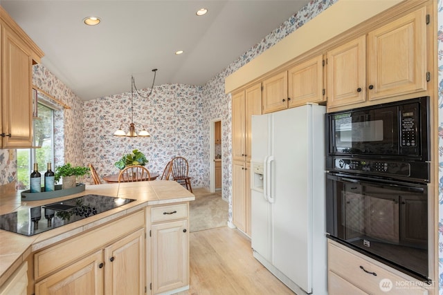 kitchen featuring black appliances, wallpapered walls, tile counters, a chandelier, and light brown cabinetry