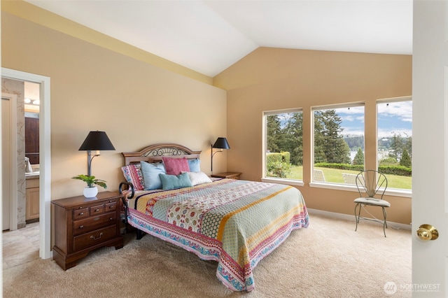 bedroom featuring light carpet, lofted ceiling, baseboards, and ensuite bathroom