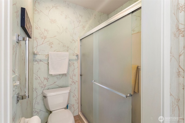 bathroom featuring wallpapered walls, a shower stall, and toilet