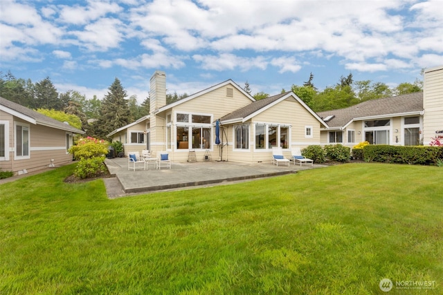 rear view of house featuring a chimney, a patio, and a yard