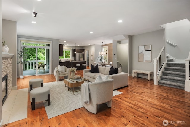 living area with recessed lighting, light wood-type flooring, and stairs