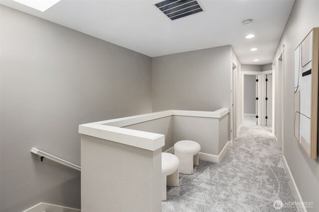 corridor featuring visible vents, baseboards, recessed lighting, carpet, and an upstairs landing