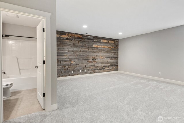 interior space with baseboards, an accent wall, and wood walls