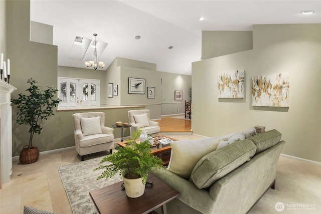 living area featuring high vaulted ceiling, an inviting chandelier, and baseboards